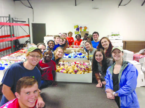 Students in University Life 100 volunteer at Help4Kids warehouse packing food for hungry children as a part of the course requirements.