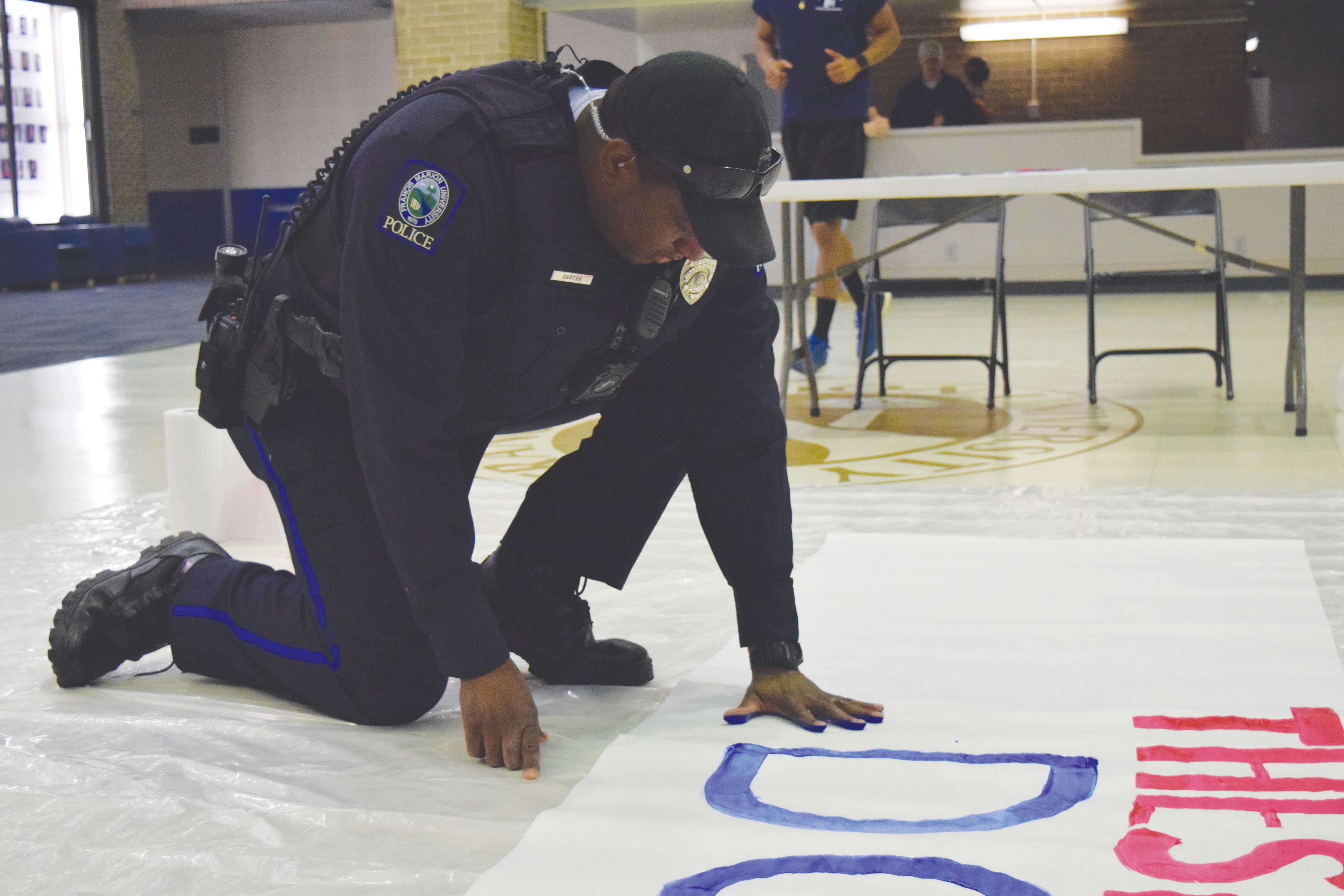 FMU campus police officer Leonza Carter places his hand print on the“These Hands Don’t Hurt” banner.