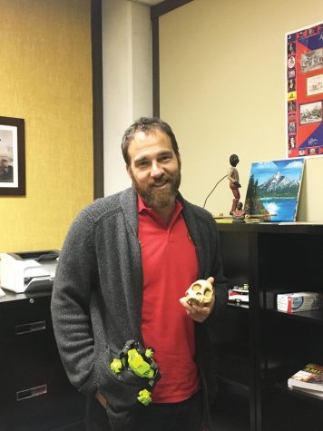 Assistant Professor of Archeology Christopher Barton poses with a skull and action figure. 