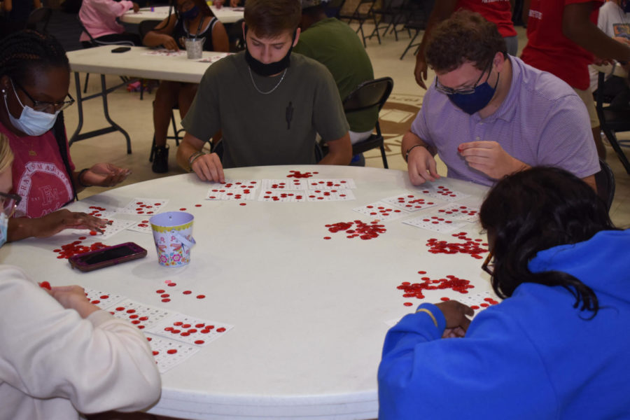 Students fill their bingo cards with circular chips after the latest number is called.