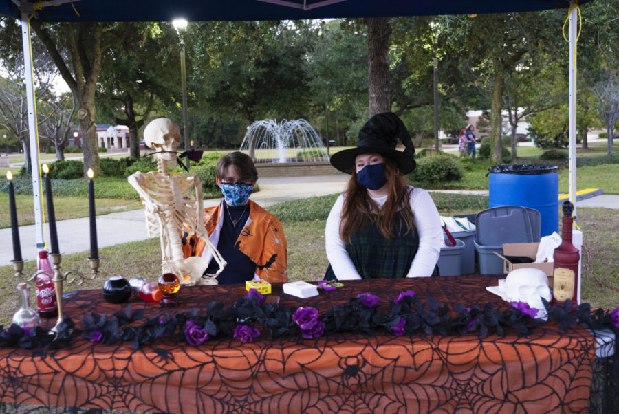 Members of Sigma Tau Alpha sit at a table laden with Halloween decorations preparing for the performances. 