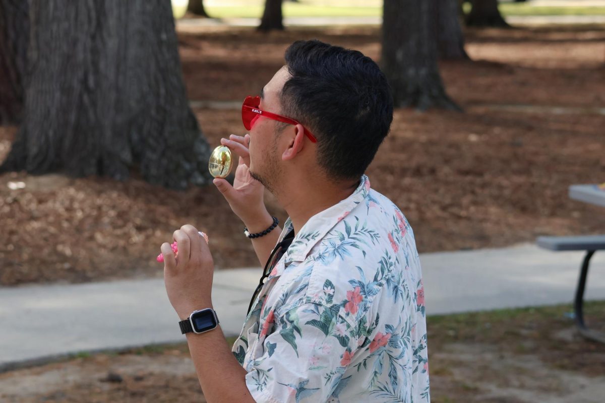 Robert Pantaleon, computer science major, finds a golden egg behind a rock during the CAB Spring Egg Hunt (April 2, 2026).